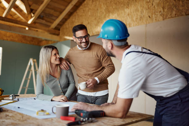 istock Happy couple talking about plans with their construction worker/ 1566594051