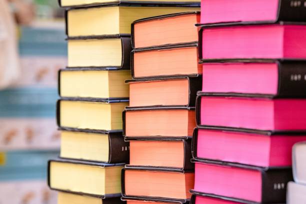 istock Stack of books with yellow, orange and pink pages arranged on stacks 1566610638