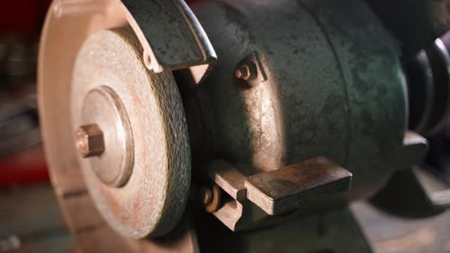Rotation of a grinding machine with an abrasive wheel close-up. Old vintage authentic machine tool in a garage workshop