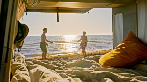 istock Couple playing badminton on beach outside camper van 1566648090