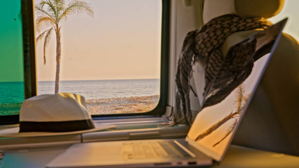 istock Interior of camper van with laptop and beach view from window 1566662422