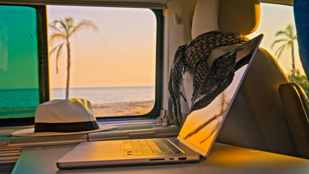 istock Interior of camper van with laptop and beach view from window 1566665541
