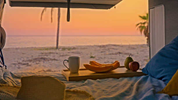 istock Fruits and coffee cup on bed in campervan at the beach 1566669337