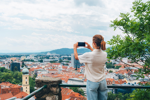 Woman tourist photographs the skyline of beautiful old european city. Graz, Austria.