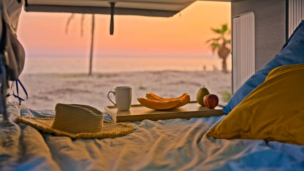istock Fruits and coffee cup on bed in campervan at the beach 1566679832