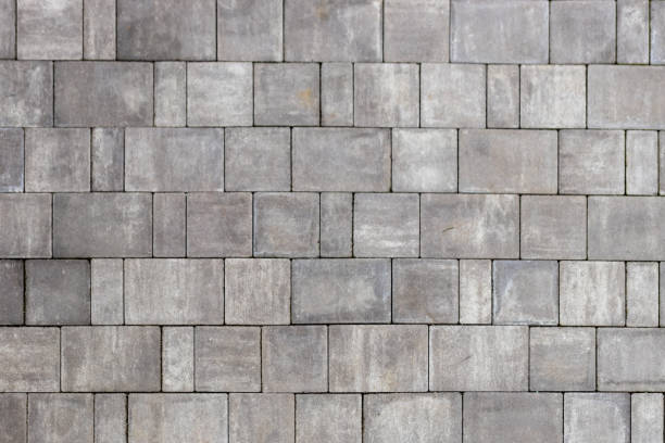 istock Gray paving stones texture. Paving surface road. Texture made of big gray cement bricks background 1566702585
