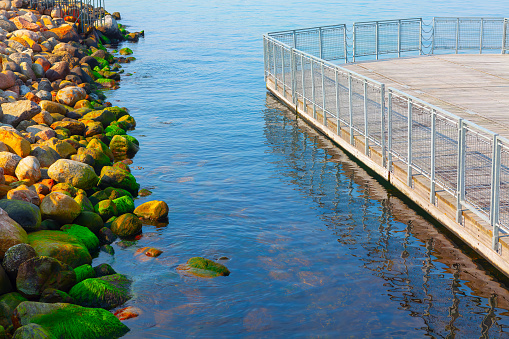 Pier in the sea with stones and green algae on it