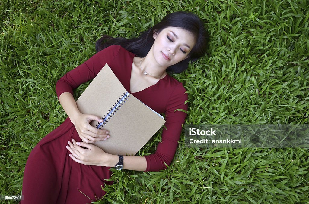 Kobieta leżąc na zielonej trawie z książki adresowej - Zbiór zdjęć royalty-free (Azja)