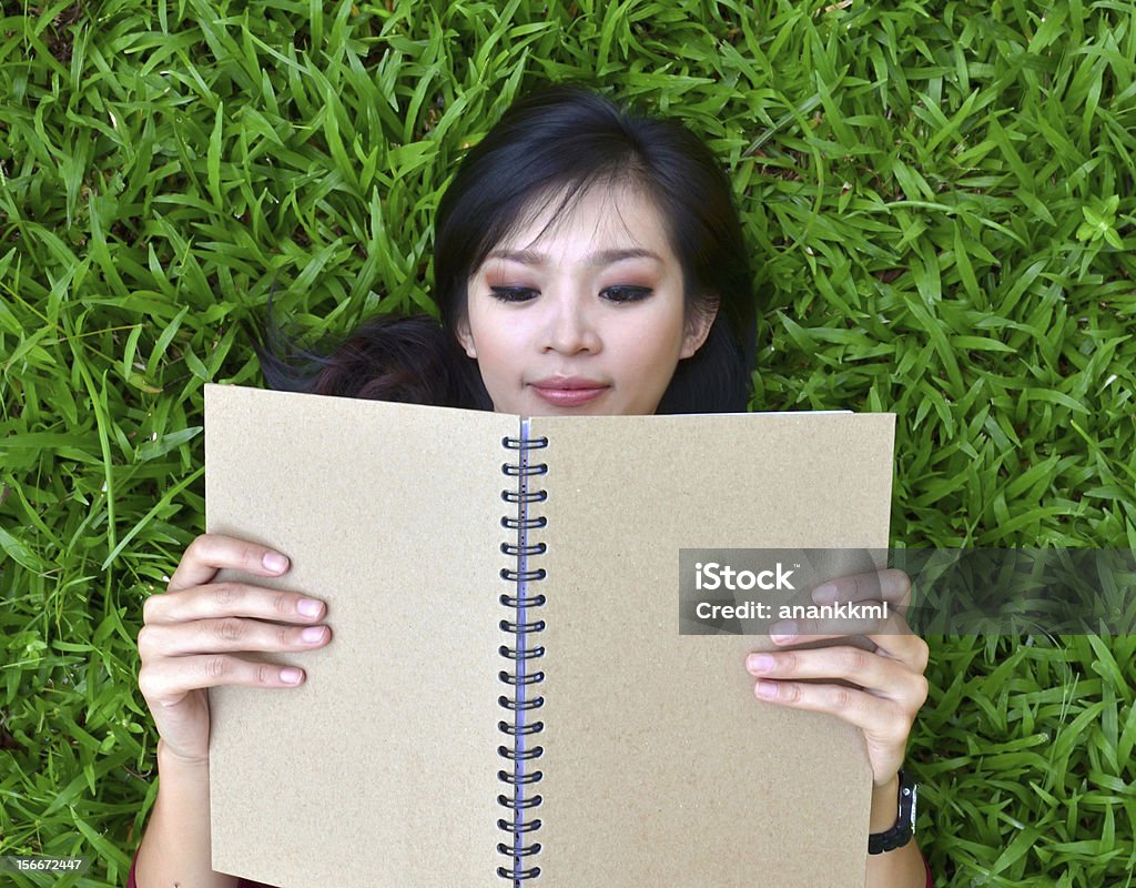 Woman lying on grass with  book Woman lying on grass with a book Adult Stock Photo