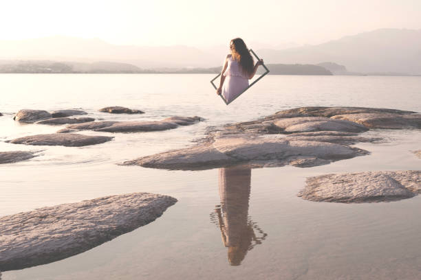 image surréaliste d’une femme retournant dans le monde réel à travers un cadre, un concept abstrait - imagination invisible women femininity photos et images de collection