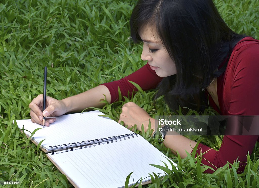 pretty women writing book pretty women lying on green grass and writing book Adult Stock Photo