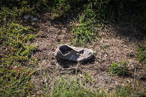 Discarded shoes in nature. Pollution and waste recycling.