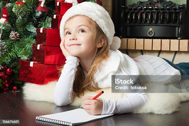 Pretty Girl In Santa Hat Writes Letter Stock Photo - Download Image Now - Letter - Document, Santa Claus, Girls