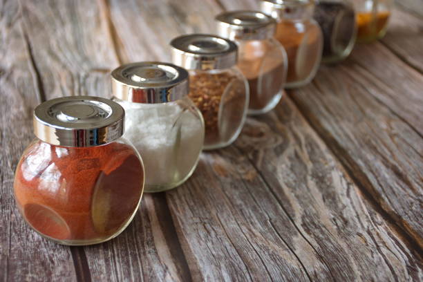 Various colorful herbs and spices in glass container on wooden background
