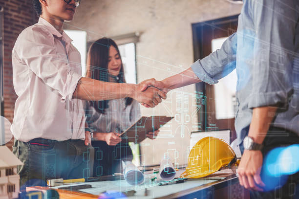 istock engineers and team shake hands around blueprint and structure with controller smart home hud. 1566756771