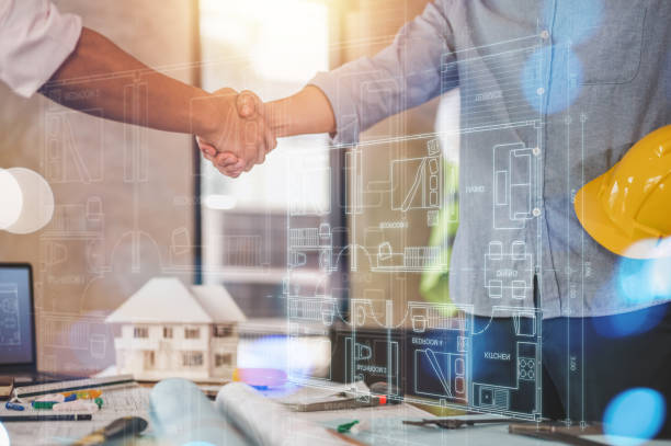 istock engineers and team shake hands around blueprint and structure with dashboard smart home hud. 1566757494