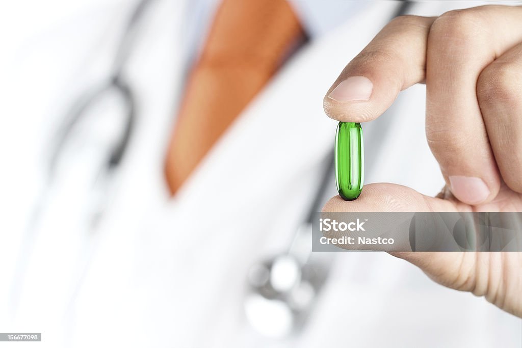 Médico segurando Verde de comprimidos - Foto de stock de Jaleco de Laboratório royalty-free