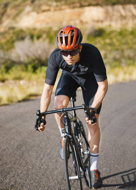 esercizio, bicicletta e ciclismo con uno sportivo su una strada attraverso la montagna per cardio o resistenza. fitness, allenamento o allenamento con un ciclista maschio in sella alla sua bicicletta su una strada asfaltata nella natura - endurance sport foto e immagini stock