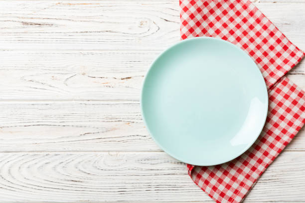 istock Top view on colored background empty round blue plate on tablecloth for food. Empty dish on napkin with space for your design 1566793317