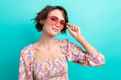 Photo of gorgeous positive lady hand touch sunglass have good mood empty space isolated on teal color background.