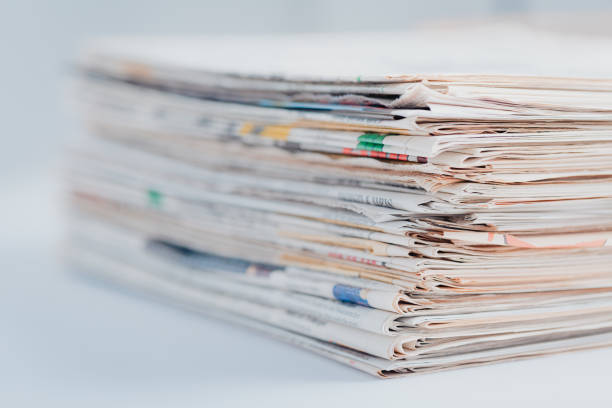 istock Pile of newspapers on table.  Folded and stacked journals. 1566811380