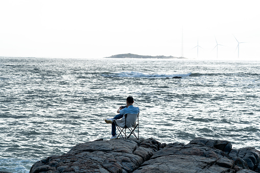 The back of a man sitting by the sea