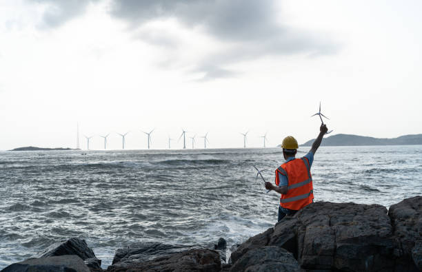 istock Offshore wind farm engineer holding the back of a model 1566813073