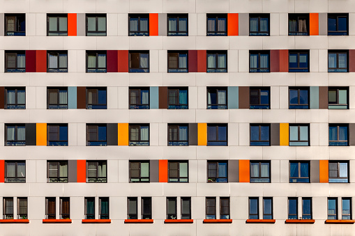 Background image wall of a modern high-rise building with windows and colorful decorative panels.