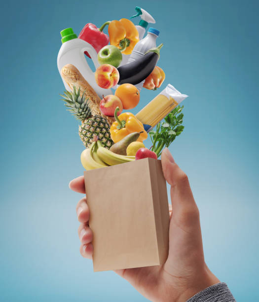 istock Customer holding a miniature grocery bag with assorted goods 1566819631
