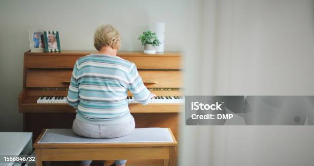 Piano Music And A Woman Playing At Home For Performance Hobby Or To Relax In A Room Behind Senior Female Person With An Old Or Vintage Instrument With Keys And Notes On Wooden Bench In A House Stock Photo - Download Image Now