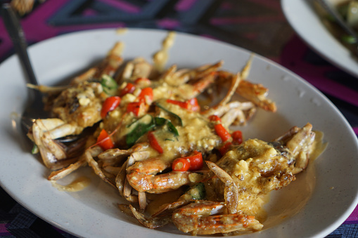 Stir fried blue crab with salted egg sauce, decorated with chili peppers and curry leaves.  Selective focus.