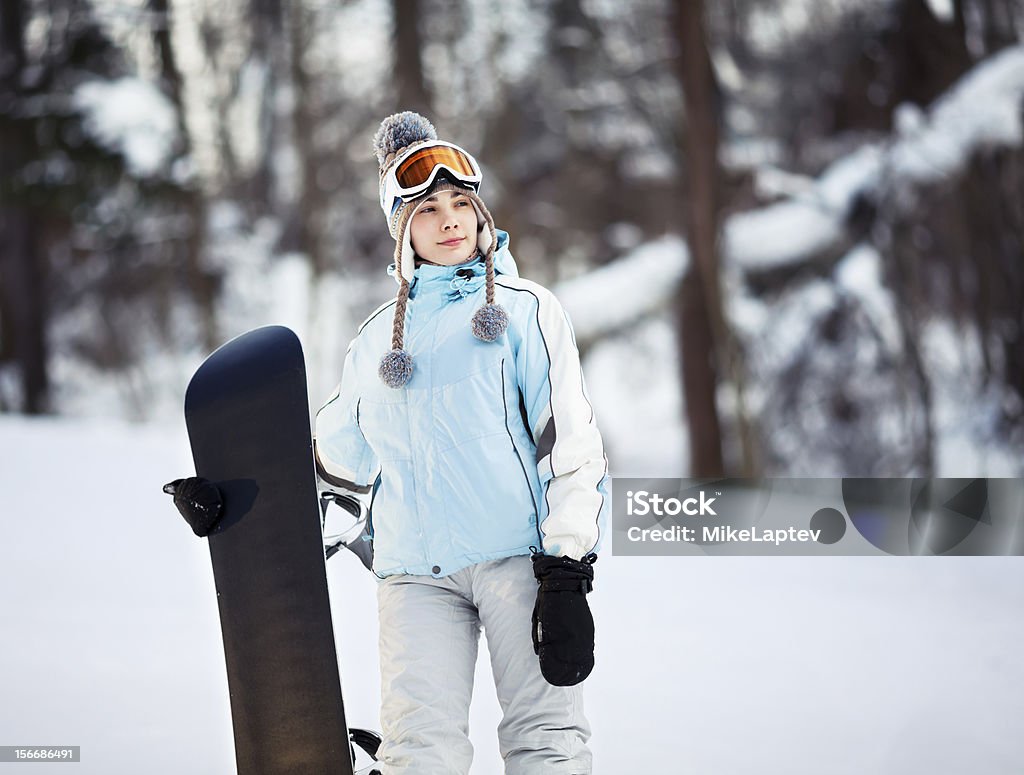 Young female snowboarder Young female snowboarder standing on ski slope holding her snowboard, she's looking away and smiling, copy space Activity Stock Photo