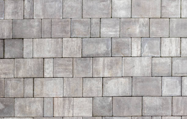 istock Gray paving stones texture. Paving surface road. Texture made of big gray cement bricks background 1566875658