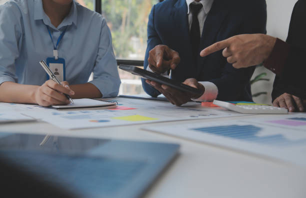 istock Financial analysts analyze business financial reports on a digital tablet planning investment project during a discussion at a meeting of corporate showing the results of their successful teamwork. 1566889287