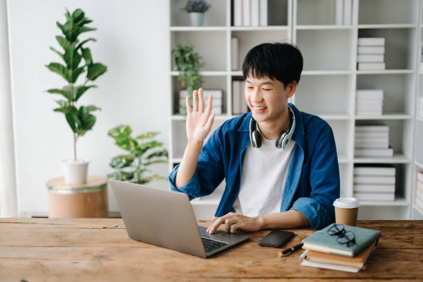 istock Young attractive Asian man smiling thinking planning writing in notebook, tablet and laptop working from home  at home office 1566889826