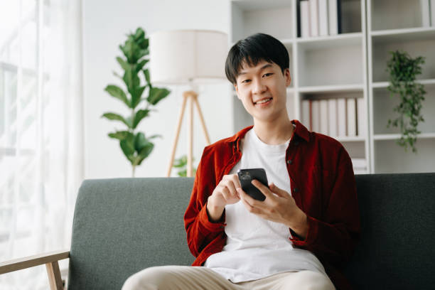istock Young attractive Asian man smiling thinking planning writing in notebook, tablet and laptop working from home  at home office 1566890895
