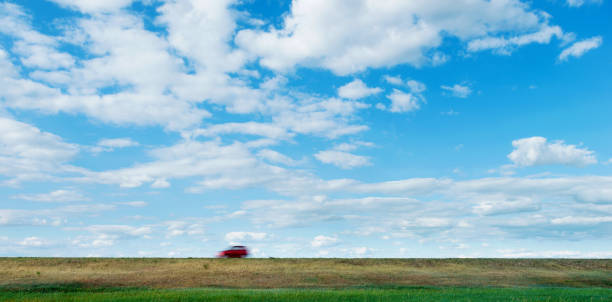 Red car driving on grassland highway