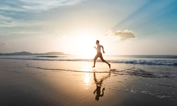 istock Man running on the beach at sunset 1566907058