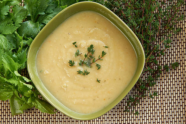 Tasty cream of celeriac soup in a green bowl Hot cream of celeriac soup in a green bowl on the table with fresh thymus and celery. Best for autumn cold and bad weather. Celeriac stock pictures, royalty-free photos & images