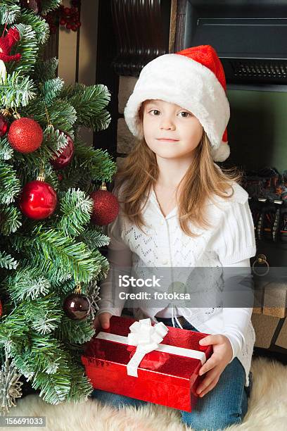 Foto de Menina De Chapéu De Papai Noel Com Presente Perto Da Árvore De Natal e mais fotos de stock de 6-7 Anos