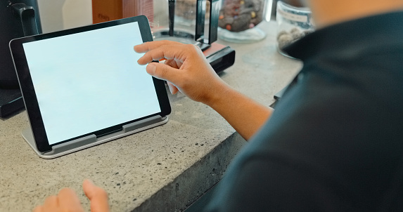 Tablet screen, barista and hands at table in cafe, working and taking order in coffee shop on mockup space. Tech, waiter man and cashier typing for sales, restaurant service or internet app in store