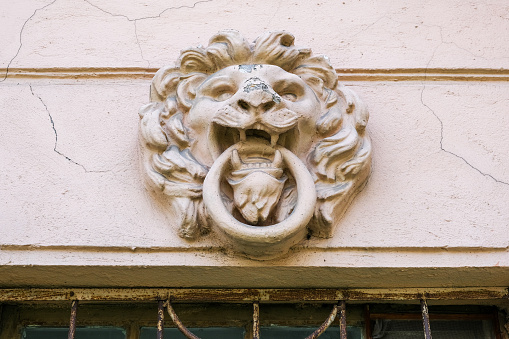 An architectural decoration depicting a lion's head with a ring in its mouth on the wall of an old building in St. Petersburg, Russia. Mascaron