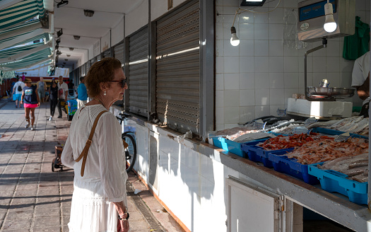 An elderly woman shopping at the fish market.