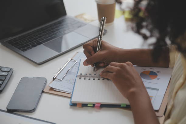 istock Asian Businesswoman Using laptop computer and working at office with calculator document on desk, doing planning analyzing the financial report, business plan investment, finance analysis concept. 1566933242