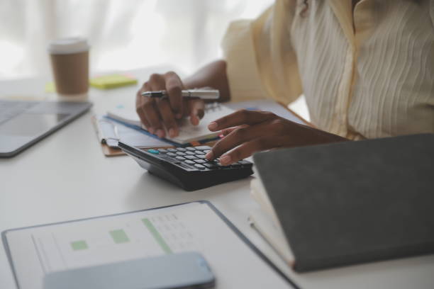 istock Asian Businesswoman Using laptop computer and working at office with calculator document on desk, doing planning analyzing the financial report, business plan investment, finance analysis concept. 1566933787