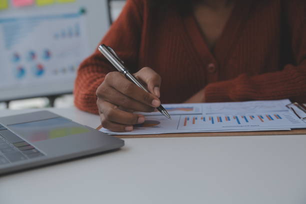 istock Asian Businesswoman Using laptop computer and working at office with calculator document on desk, doing planning analyzing the financial report, business plan investment, finance analysis concept. 1566937114