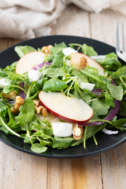 istock Autumn salad with apples and walnuts on wooden table 1566941060