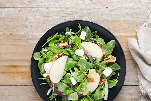 Autumn salad with apples and walnuts on wooden table