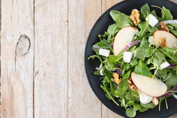 istock Autumn salad with apples and walnuts on wooden table 1566942924