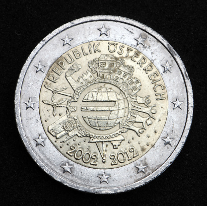 Back, national side of 2 Euro coin from Austria shows world in the form of a euro symbol, family, Eurotower, ship, factory, and two wind turbines, minted in 2012, commemorative coin